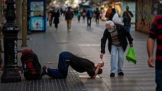 Un passant donne de l'argent à un mendiant sur les Remblas à Barcelone, le 12 novembre 2020