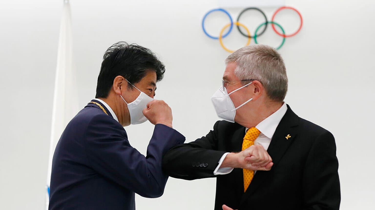 Former Japan's Prime Minister Shinzo Abe, left, and Thomas Bach, President of the International Olympic Committee (IOC), bump elbows in Tokyo