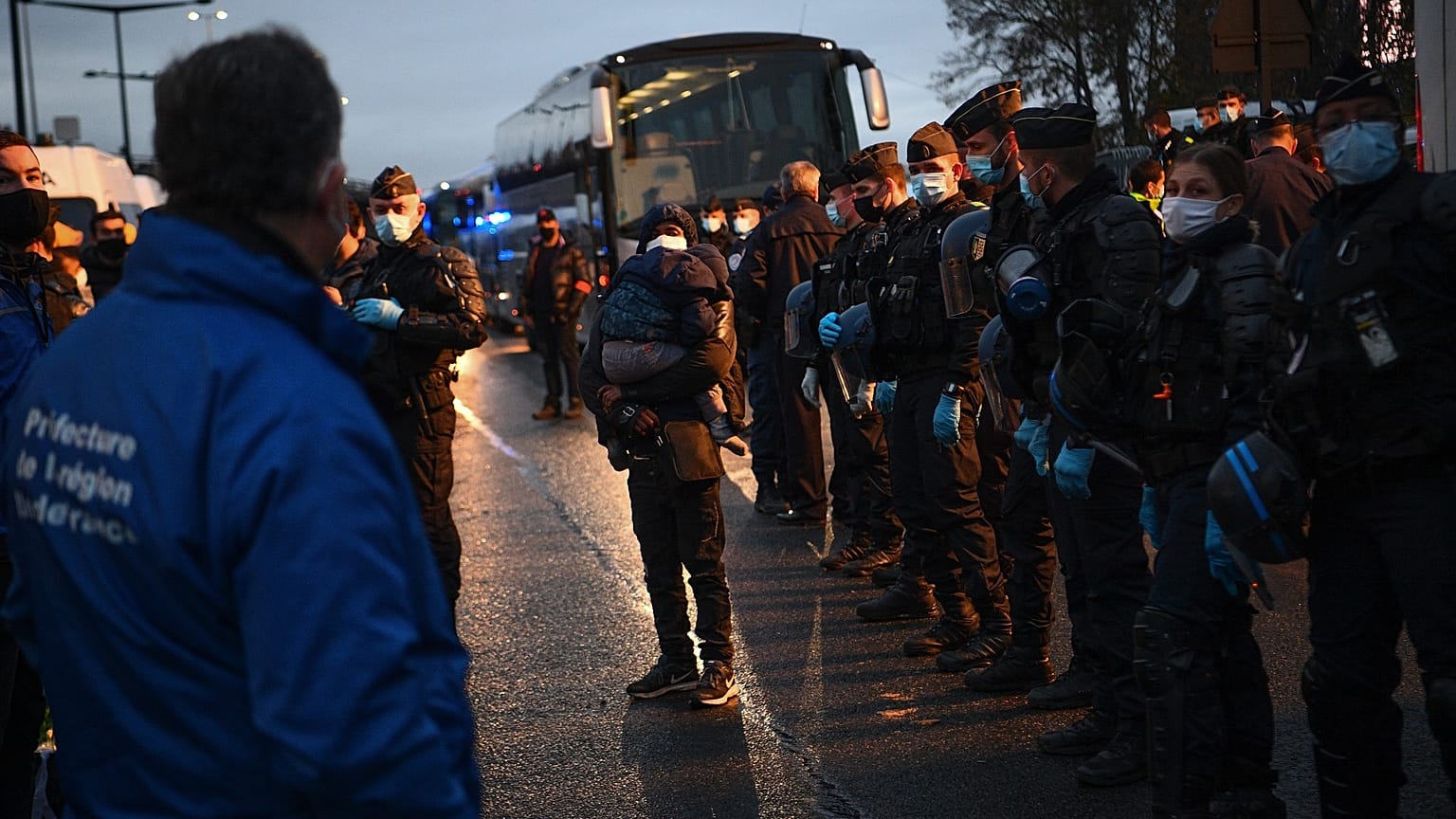Migrants wait to be evacuated by Gendarmerie forces at a makeshift camp set below the motorway in Saint-Denis, France, on Nov. 17, 2020.