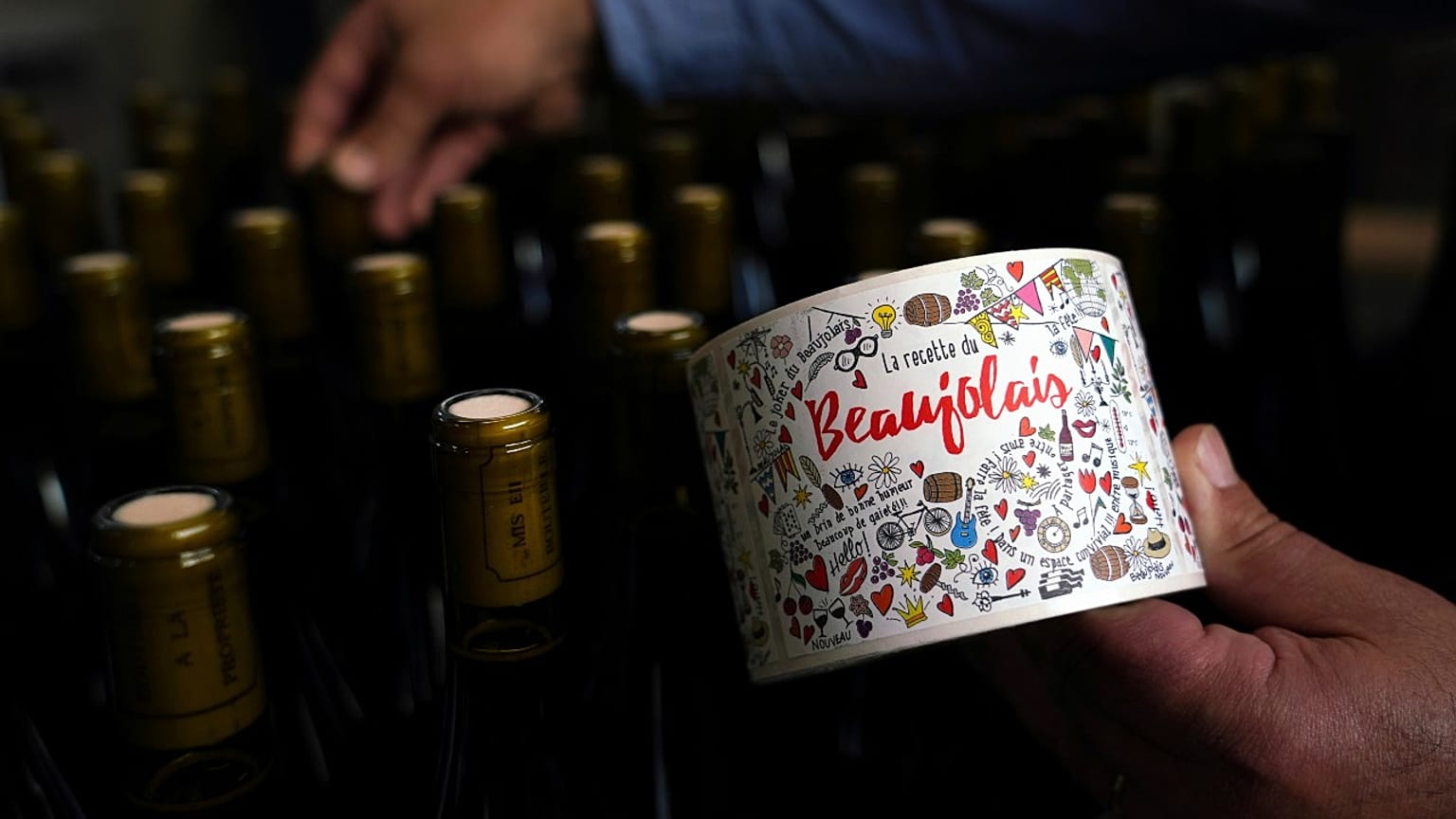 Tuesday, Nov. 12, 2019, a man picks a bottle of Beaujolais Nouveau in the Vinescence cellar in Saint Jean d'Ardieres, in the Beaujolais region