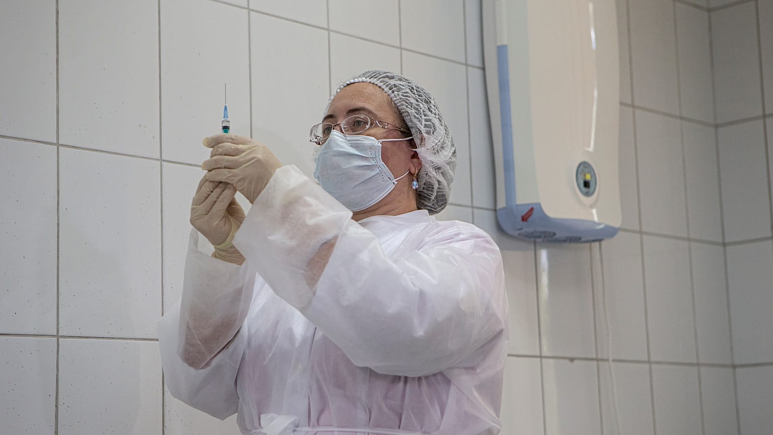 Медсестра готовится к введению экспериментальной вакцины или плацебо волонтёру
