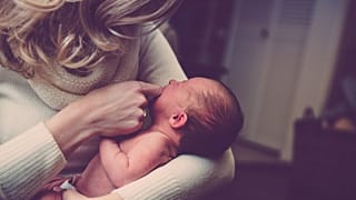A woman holds a newborn baby.