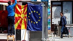 Ein Straßenhändler befestigt eine nordmazedonische Flagge neben einer EU-Flagge in einer Straße in Skopje, 3. Mai 2019