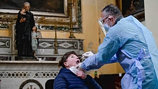 A medical operator performs COVID-19 test swabs in the Church of San Severo Outside the Walls, in the heart of Naples, Italy, Wednesday, Nov. 18, 2020.