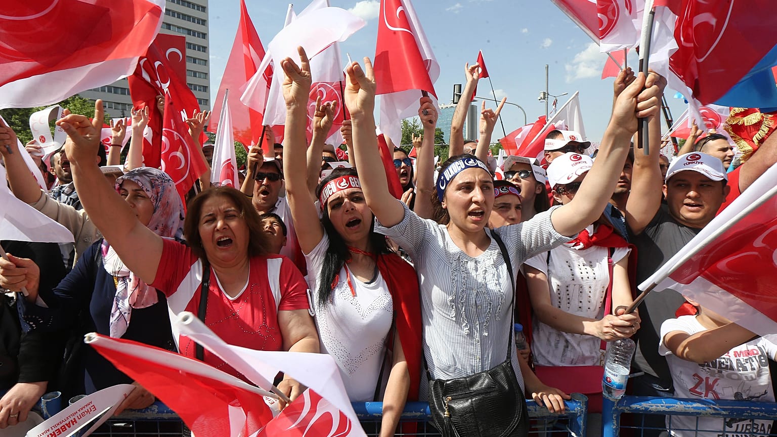 People gestures the "Grey Wolves" salutation and wave flafs during an election rally of Turkey's opposition Nationalist Action Party (MHP) May 24, 2015 in Ankara,