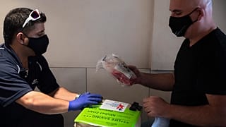 Dorme negli aeroporti vuoti e riparte subito dopo la consegna per evitare la quarantena: Mishel Zrian, corriere israeliano (a dx) riceve il midollo osseo da trasportare.