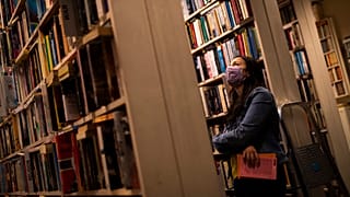 A woman wears a face mask, to protect against the spread of coronavirus, as she browses for books in a second-hand bookshop in Brussels, June 11, 2020.