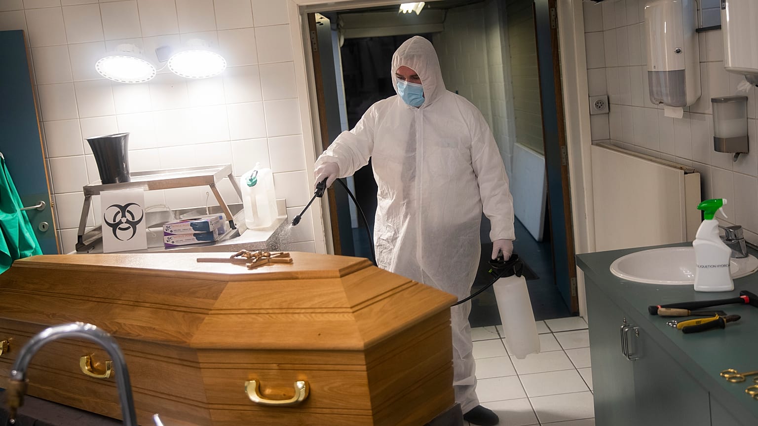 A worker, wearing a full protective equipment, disinfects the casket of someone who died of coronavirus COVID-19 at a funeral home in Charleroi, Belgium, Nov 17, 2020.