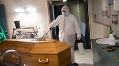 A worker, wearing a full protective equipment, disinfects the casket of someone who died of coronavirus COVID-19 at a funeral home in Charleroi, Belgium, Nov 17, 2020.