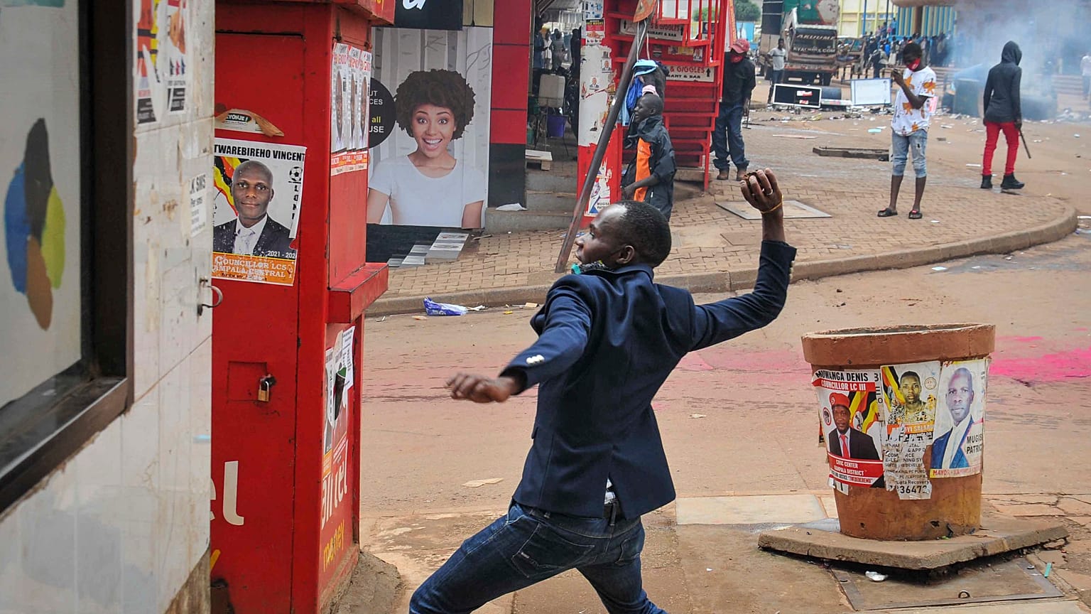 A person prepares to throw a rock during clashes between security forces and protesters supporting opposition presidential candidate Bobi Wine