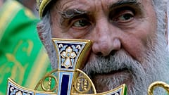 In this May 24, 2012, file photo, Serbian Orthodox Church Patriarch Irinej holds a cross during a procession marking Belgrade's patrons saint day, Spasovdan, in Belgrade