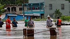 Hombres caminan por una calle inundada después del paso del huracán Iota en La Lima, Honduras