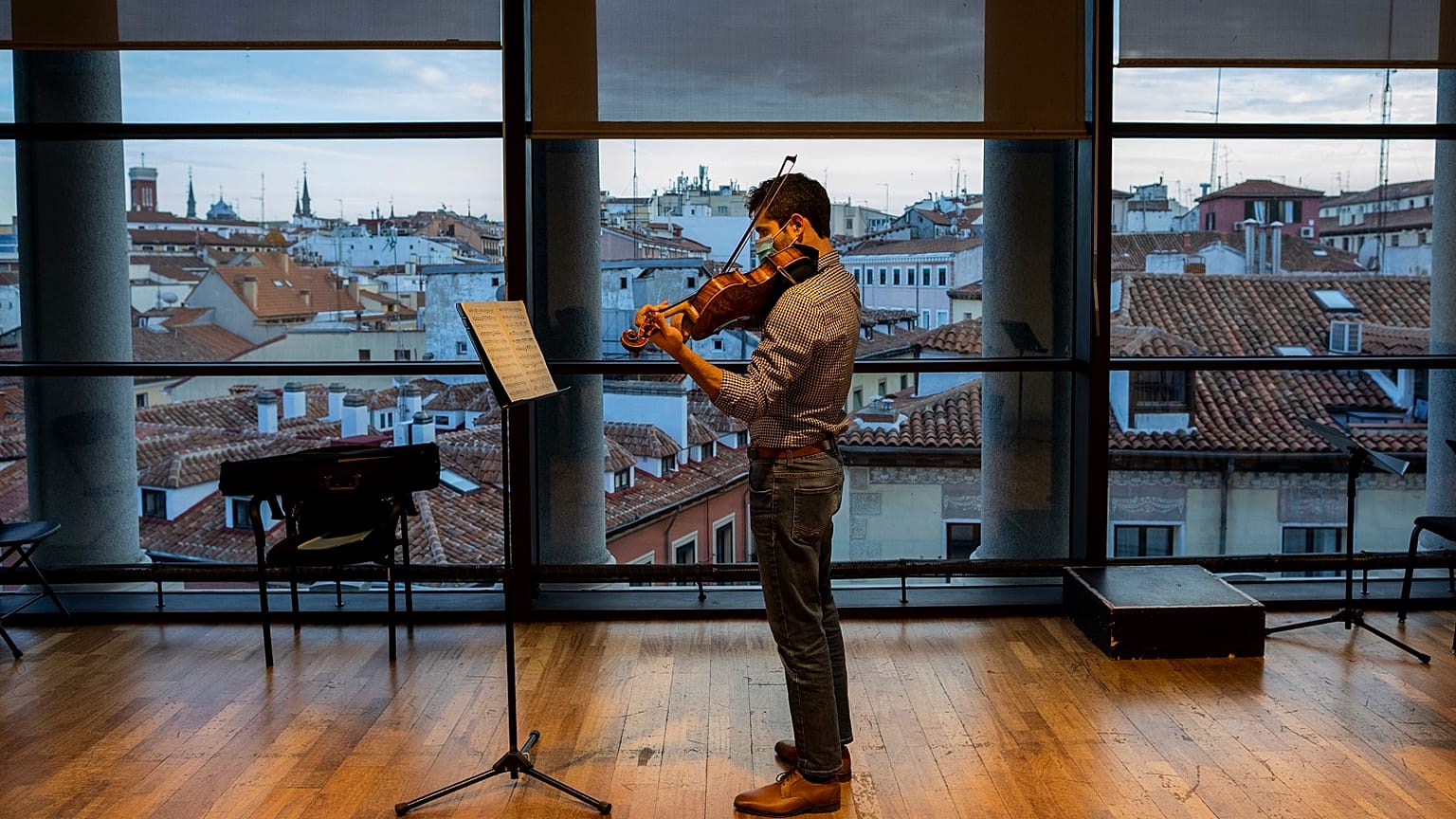 A musician in a face mask plays the violin at a rehearsal at the Teatro Real in Madrid, Spain, Friday, November 13, 2020.
