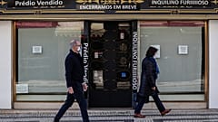 Traseuntes passam por uma loja fechada na zona da baixa pombalina de Lisboa