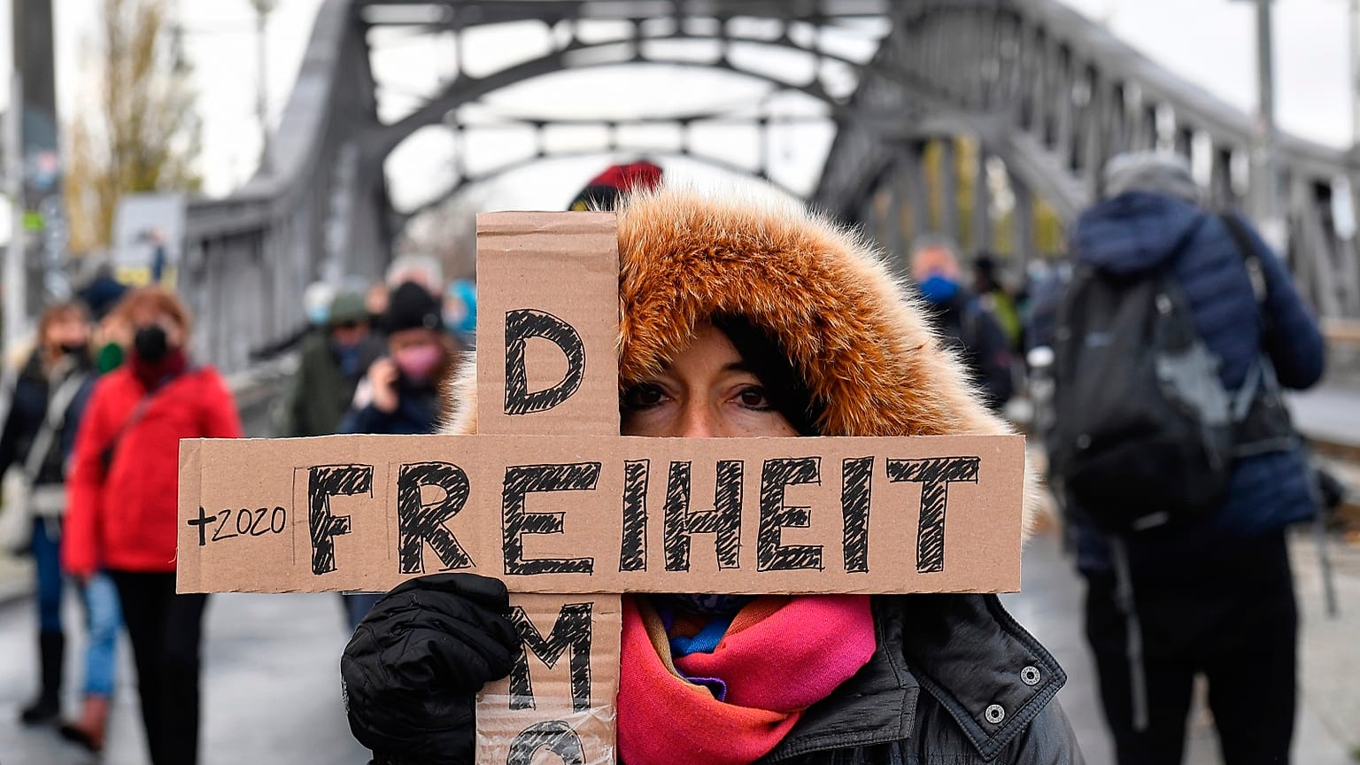 A woman attending a silent march against measures to curb the spread of coronavirus holds a cross reading "Freedom democracy" in Berlin on November 22, 2020.