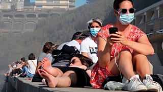 People sunbathe near the Atlantic ocean in Biarritz, southwestern France, Sunday, Nov. 1, 2020.