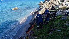 Firefighters retrieve the body of a migrant from the beach after the boat partially sank near the Greek island of Rhodes.