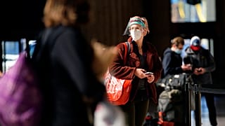 A woman waits in line for a train at the 30th Street Station ahead of the Thanksgiving holiday, Friday, Nov. 20, 2020, in Philadelphia.