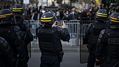 A French riot police officer photographs protesters with his phone during a demonstration in Marseille, southern France, Saturday, Nov. 21, 2020.