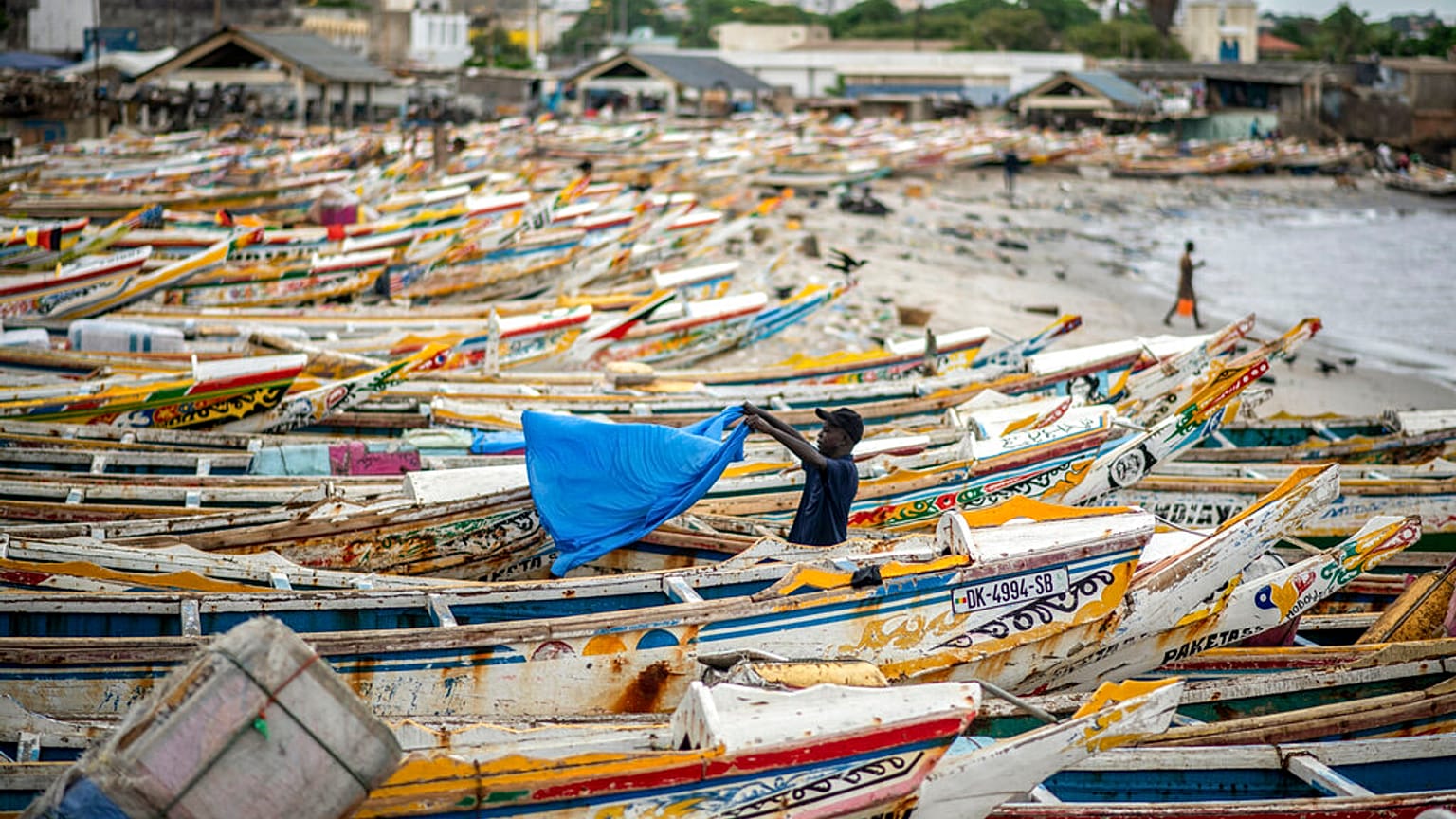 Ein Fischer trocknet ein Tuch neben den Fischerbooten in Dakar, Senegal, 30.07.2020