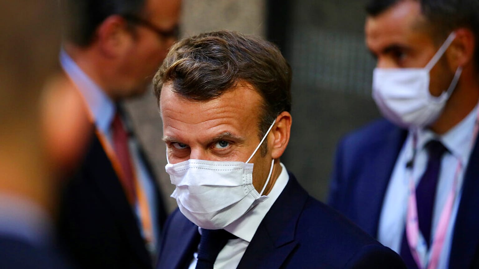 French President Emmanuel Macron, center, leaves the European Council building in the early morning during an EU summit in Brussels, Monday, July 20, 2020