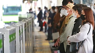 People wearing face masks to protect against the spread of the coronavirus wait for train at a station in Tokyo