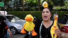 Mid shot vender selling a yellow duck -- a protest symbol -- and yellow chicken for sale