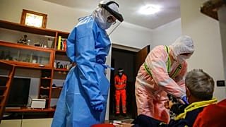 Medical staffer Ruggero Gariboldi, right, measures oxygen level in the blood of a suspected Covid patient