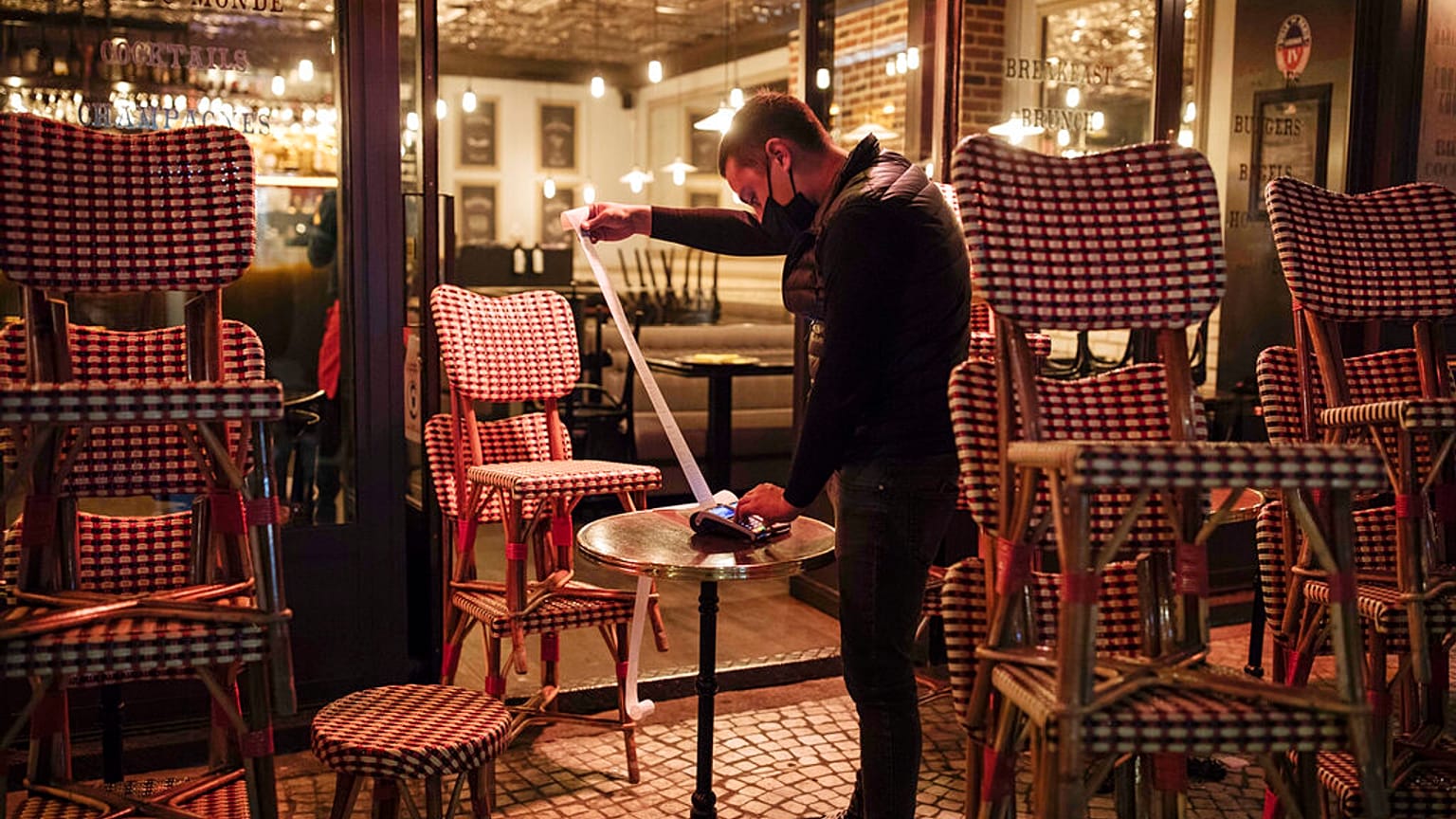A waiter checks the final revenue as he closes a bar terrace in Paris, Saturday, Oct. 17