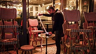 A waiter checks the final revenue as he closes a bar terrace in Paris, Saturday, Oct. 17