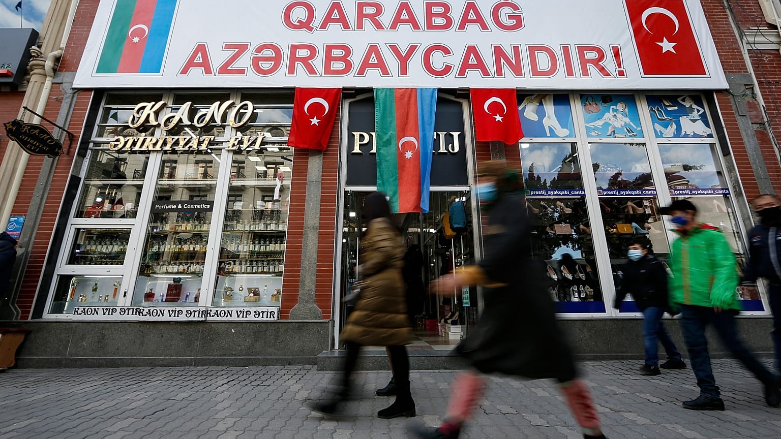People walk past a poster reading "Karabakh is Azerbaijan" in Ganja, Azerbaijan's second largest city, near the border with Armenia, Azerbaijan, Thursday, Nov. 26, 2020.