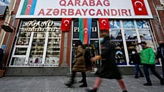 People walk past a poster reading "Karabakh is Azerbaijan" in Ganja, Azerbaijan's second largest city, near the border with Armenia, Azerbaijan, Thursday, Nov. 26, 2020.