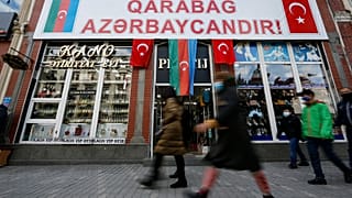People walk past a poster reading "Karabakh is Azerbaijan" in Ganja, Azerbaijan's second largest city, near the border with Armenia, Azerbaijan, Thursday, Nov. 26, 2020.