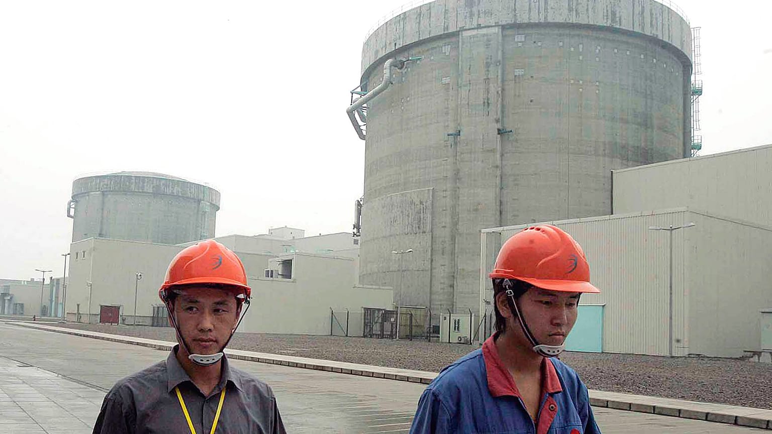 workers walk past a part of the Qinshan No. 2 Nuclear Power Plant, China's first self-designed and self-built national commercial nuclear power plant in Qinshan
