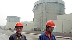 workers walk past a part of the Qinshan No. 2 Nuclear Power Plant, China's first self-designed and self-built national commercial nuclear power plant in Qinshan