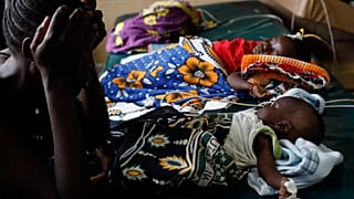 Kenya'nın batısında sıtma rahatsızlığına yakalanan çocuğuna bakan bir kadın (arşiv)