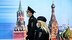 Сотрудники полиции идут мимо фотографии Спасской башни и Собора Василия Блаженного в аэропорту Шереметьево