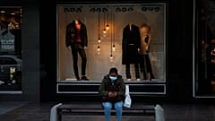 A woman wearing face mask sits on a bench at a main shopping street in capital Nicosia
