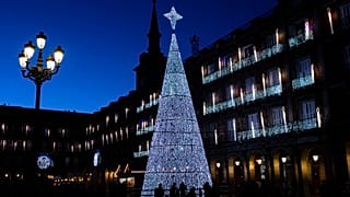 Pedestrians are silhouetted in front of a giant Christmas tree at the Plaza Mayor, Madrid, Spain