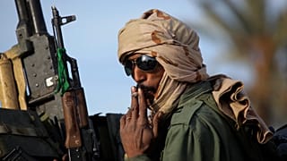 a pro-Gadhafi soldier smoke a cigarette on the top of a tank on the main square of Zawiya, Libya, 50 kms (30 miles) west of Tripoli, Friday, March 11, 2011