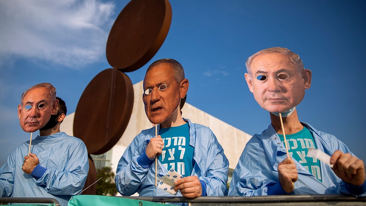 Israeli demonstrators hold masks depicting Benjamin Netanyahu and Benny Gantz during a protest against a vote to dissolve the Knesset.