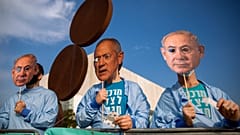 Israeli demonstrators hold masks depicting Benjamin Netanyahu and Benny Gantz during a protest against a vote to dissolve the Knesset.