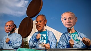 Israeli demonstrators hold masks depicting Benjamin Netanyahu and Benny Gantz during a protest against a vote to dissolve the Knesset.