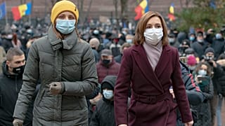 Moldova's president elect Maia Sandu, right, walks away after addressing protesters outside the parliament building in Chisinau, Moldova, Thursday, December 3, 2020.