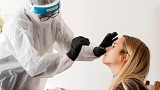 Koronavírus-teszthez vesz mintát egy egyetemi hallgató a győrszentiváni Hungaro-Dalton Pedagógiai Innovációs Egyesület egyik dolgozójától 2020. december 1-én
