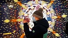 A visitor wearing a face mask to help curb the spread of the coronavirus looks at her smartphone as she walks in the GUM State Department store in Moscow