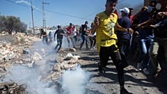 فلسطينيون يفرون من الغاز المسيل للدموع خلال تظاهرة في الضفة الغربية المحتلة
