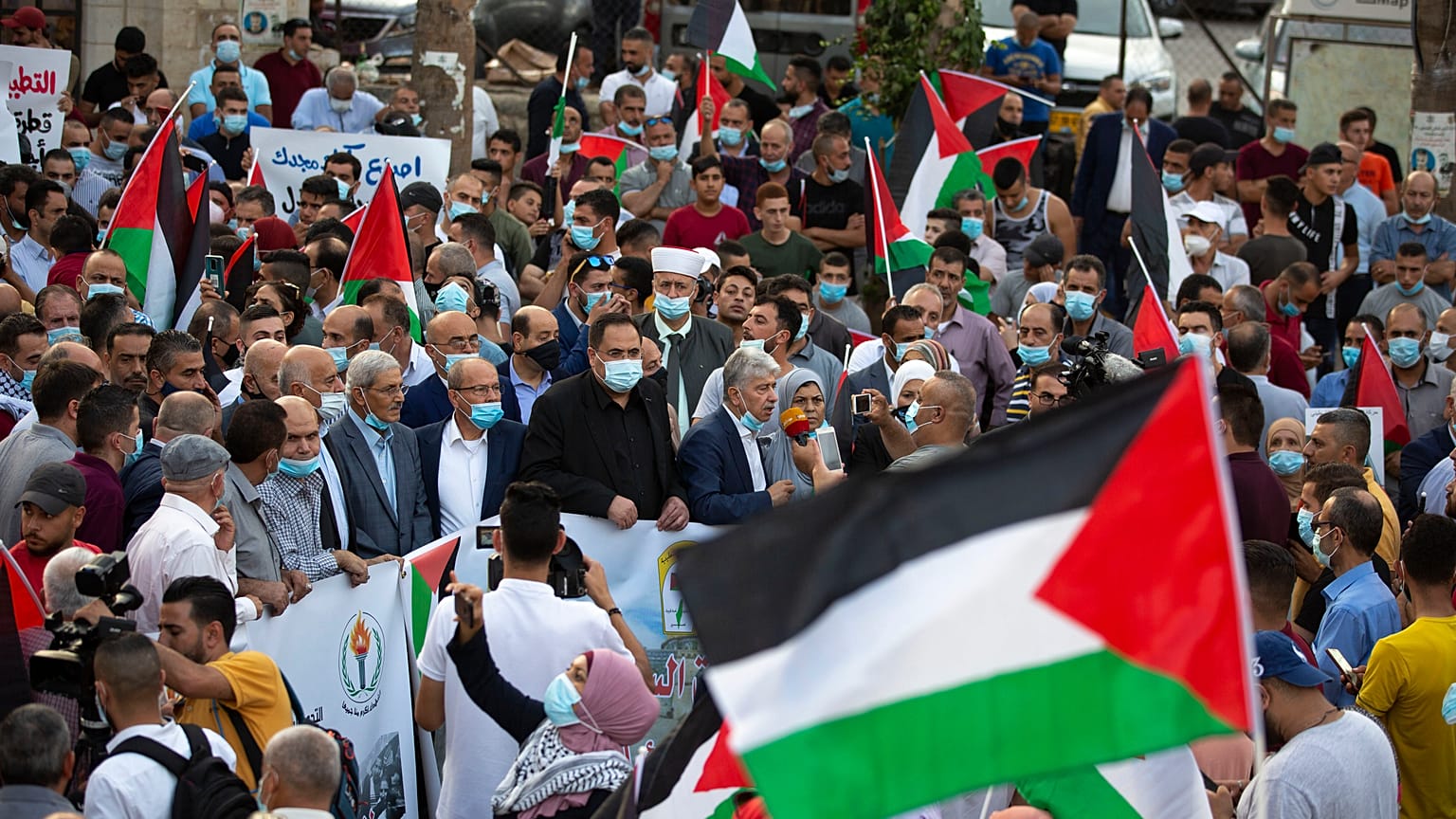فلسطينيون يلوحون بالأعلام احتجاجاً على تطبيع العلاقات بين الإمارات العربية المتحدة والبحرين مع إسرائيل، رام الله بالضفة الغربية