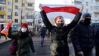 A protester waves an old Belarusian national flag, during an opposition rally against the official presidential election results in Minsk, Belarus, Sunday, Dec. 6, 2020.