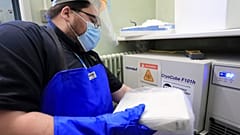 A pharmacy technician from Croydon Health Services takes delivery of the first batch of COVID-19 vaccinations at Croydon University Hospital in south London.
